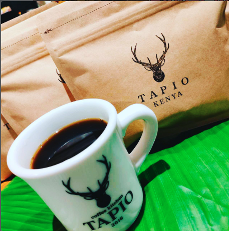 TAPIOの鹿のロゴ入りカップに注がれたコーヒーとコーヒーの袋